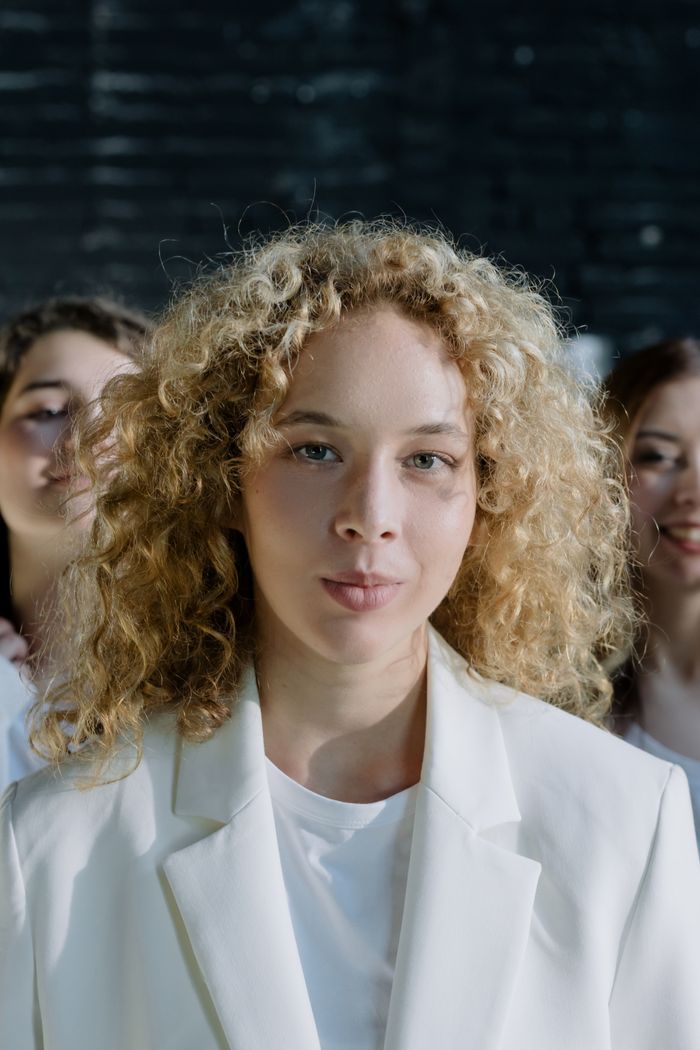 Three women with curly hair in a studio, highlighting diverse beauty and unity.