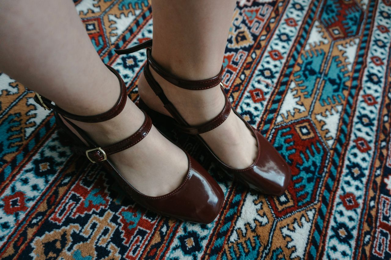 Stylish brown shoes on a traditional patterned carpet showcasing elegance and culture.