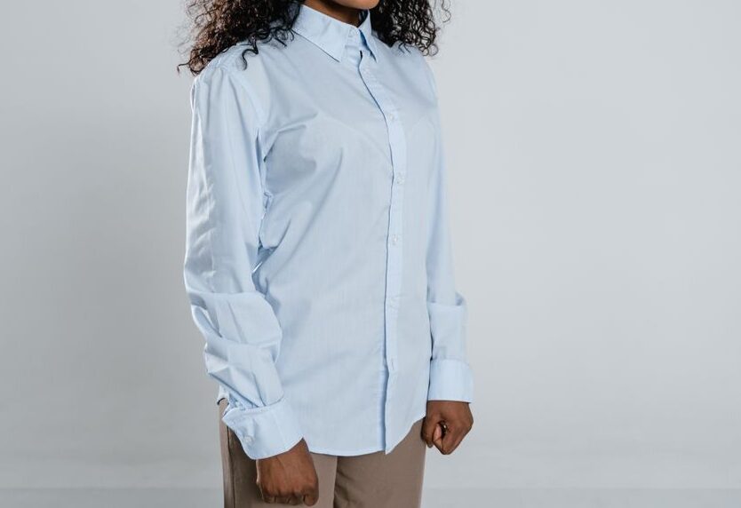 Confident woman with curly hair and a blue shirt, standing against a neutral background.